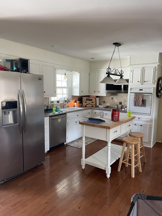 kitchen featuring dark wood finished floors, white cabinets, appliances with stainless steel finishes, and a sink