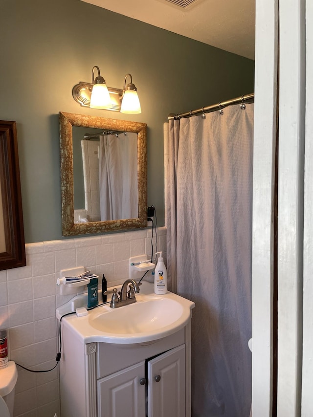 bathroom featuring vanity, tile walls, and wainscoting