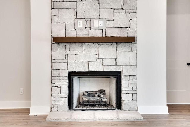 room details with a stone fireplace, baseboards, and wood finished floors