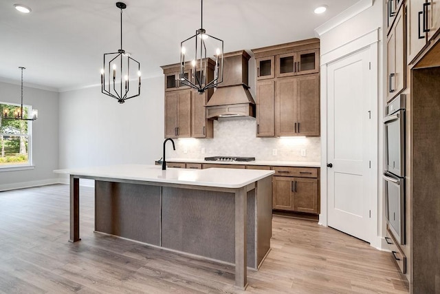 kitchen featuring premium range hood, light countertops, ornamental molding, decorative backsplash, and stainless steel appliances