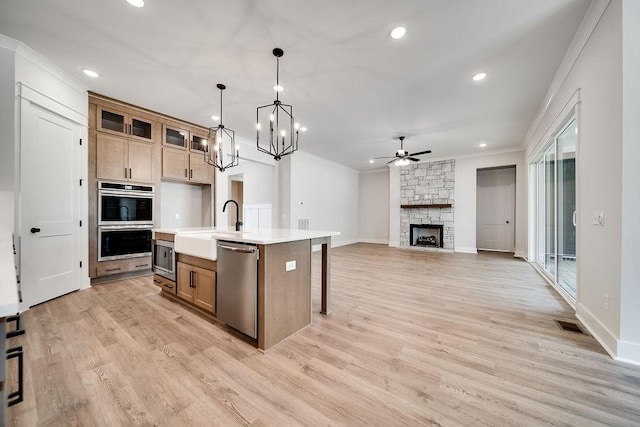 kitchen featuring a fireplace, a sink, stainless steel appliances, light countertops, and crown molding