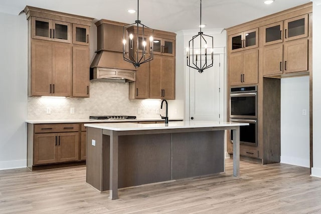 kitchen with stainless steel double oven, light wood finished floors, decorative backsplash, custom exhaust hood, and light countertops