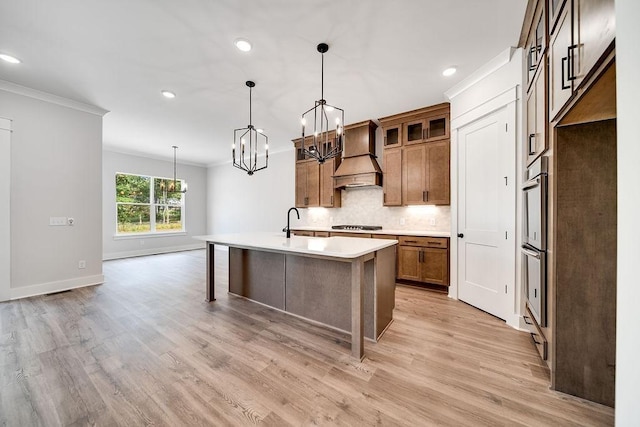 kitchen with tasteful backsplash, crown molding, light countertops, custom exhaust hood, and a notable chandelier