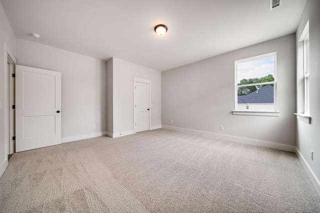 unfurnished bedroom with visible vents, baseboards, and light colored carpet