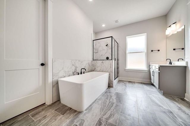 bathroom with vanity, visible vents, a freestanding tub, a shower stall, and tile walls