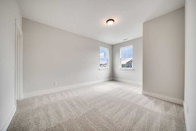 unfurnished room with baseboards, light carpet, and visible vents