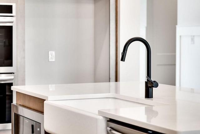 interior details with a sink, dishwasher, and light countertops