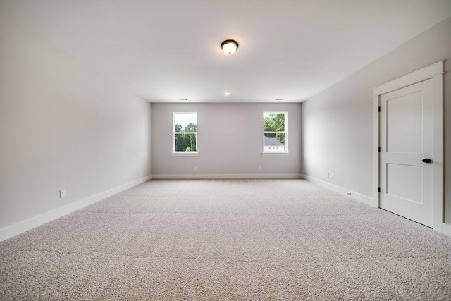 empty room featuring baseboards and light carpet