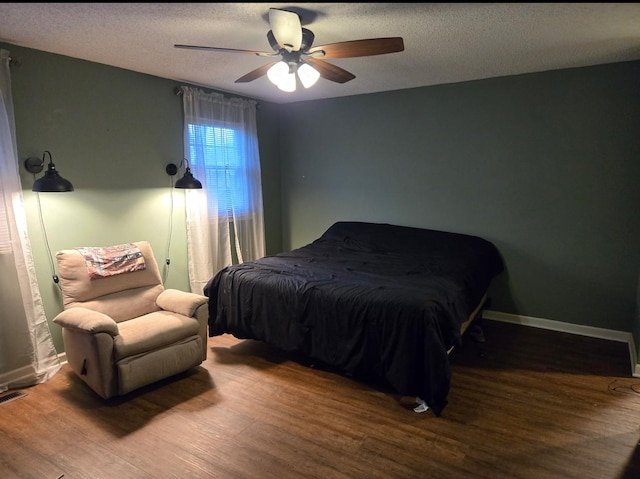 bedroom with ceiling fan, baseboards, a textured ceiling, and wood finished floors