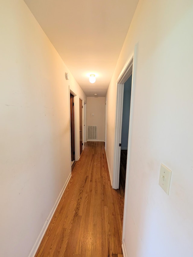 corridor featuring visible vents, light wood-style floors, and baseboards