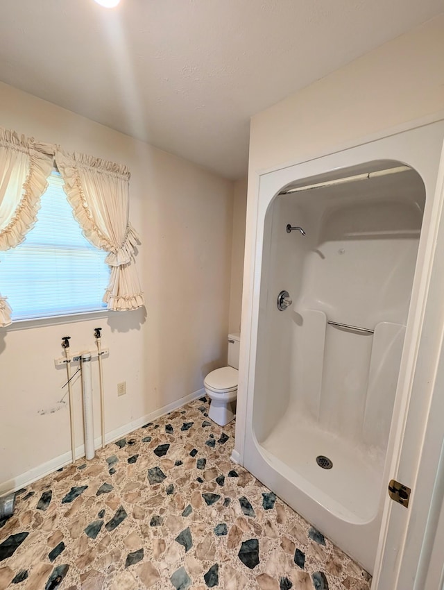 full bathroom featuring toilet, a shower, and baseboards