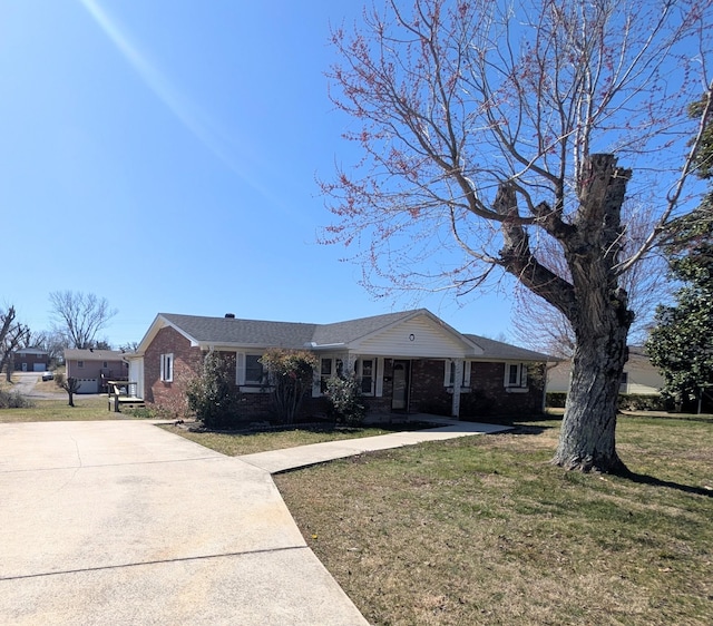 single story home with concrete driveway, brick siding, and a front yard