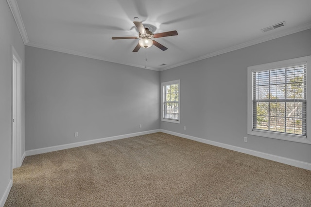 carpeted empty room with visible vents, ceiling fan, crown molding, and baseboards