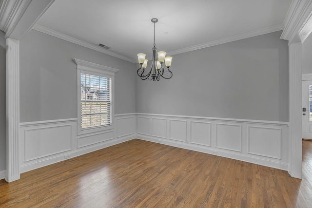 unfurnished room with visible vents, ornamental molding, an inviting chandelier, and wood finished floors