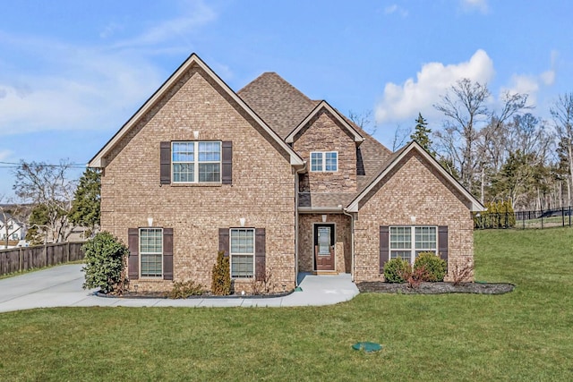 view of front of property with a front lawn, fence, brick siding, and a shingled roof