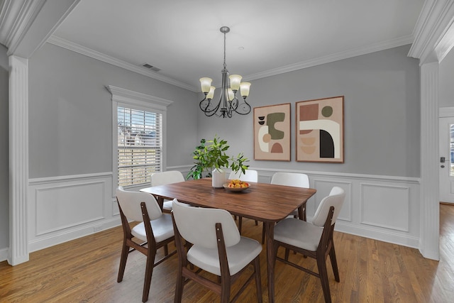 dining area featuring crown molding, a notable chandelier, wood finished floors, and visible vents