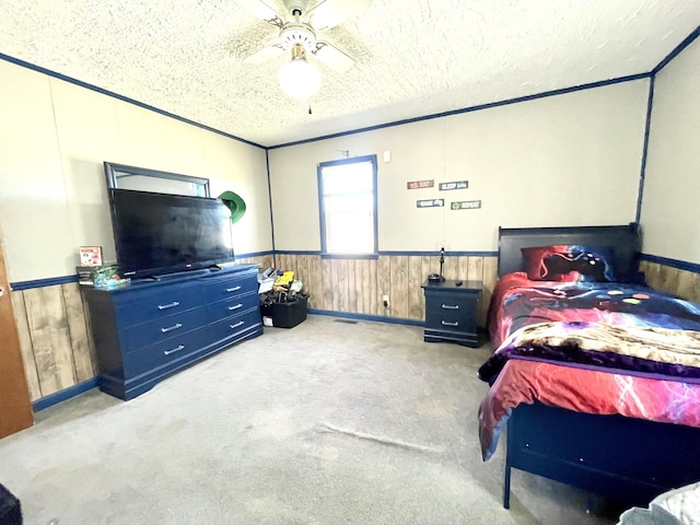 bedroom with wooden walls, a ceiling fan, carpet floors, wainscoting, and a textured ceiling