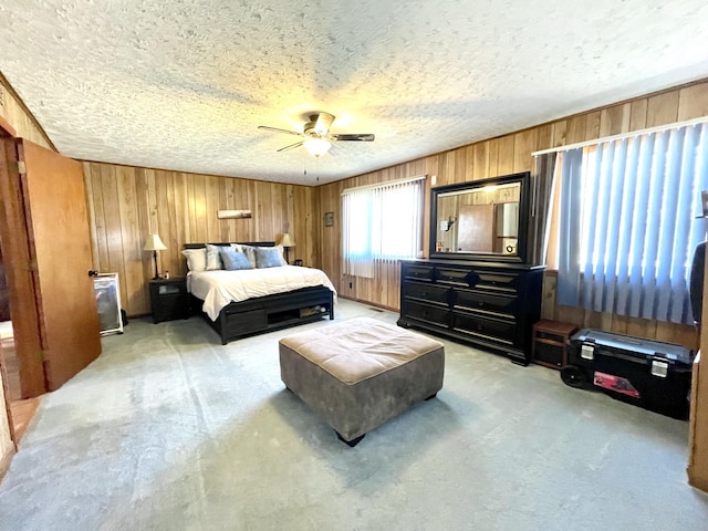 bedroom with ceiling fan, carpet floors, a textured ceiling, and wood walls