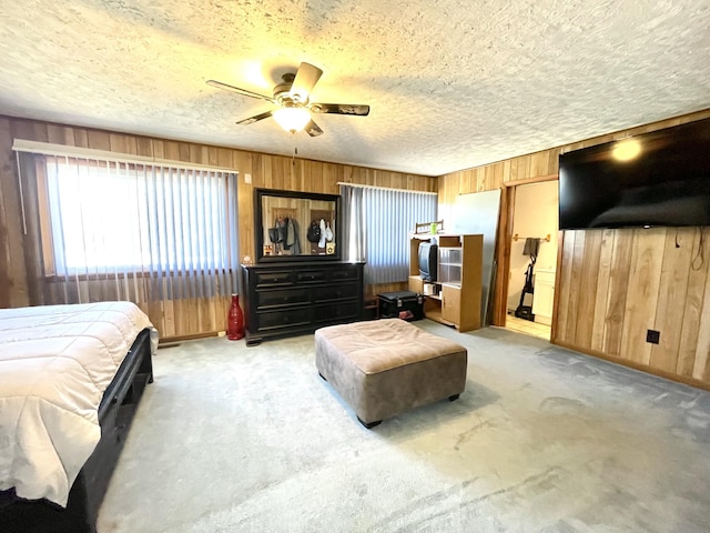 bedroom with wooden walls, light colored carpet, a textured ceiling, and a ceiling fan