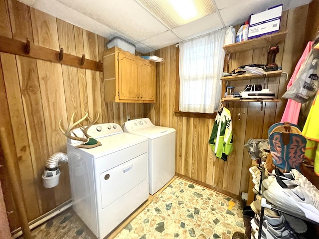 laundry area with cabinet space, wood walls, and washing machine and clothes dryer