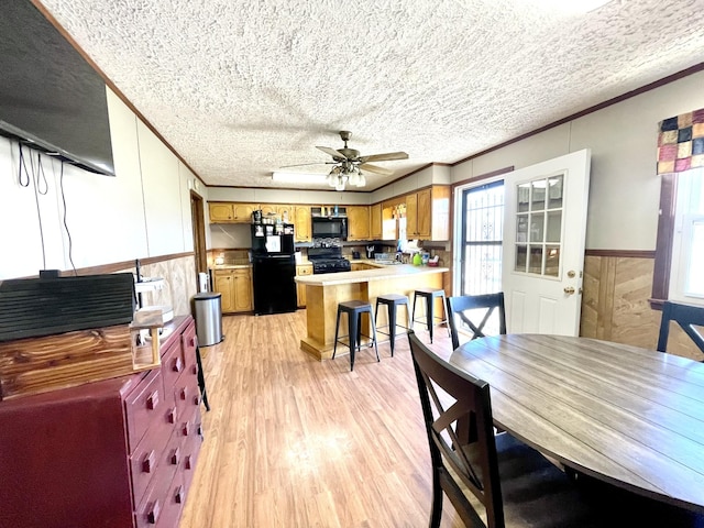 interior space with a peninsula, light wood-style flooring, black appliances, a textured ceiling, and crown molding