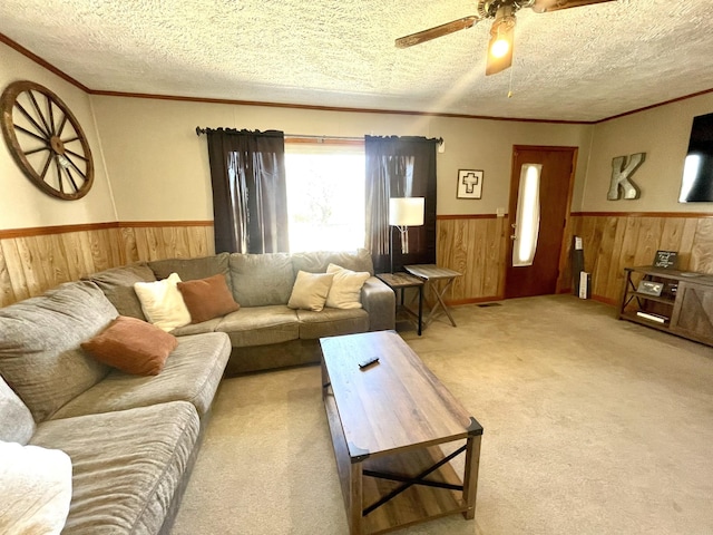 living room featuring a wainscoted wall, light colored carpet, wooden walls, and a textured ceiling