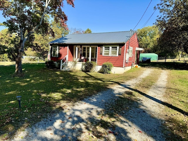 view of front of house featuring a front lawn, covered porch, driveway, and metal roof