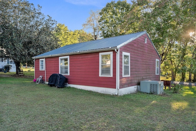 view of side of home with central air condition unit, a yard, and metal roof