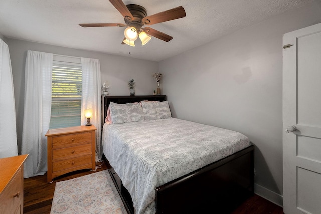 bedroom with a textured ceiling, dark wood finished floors, and a ceiling fan