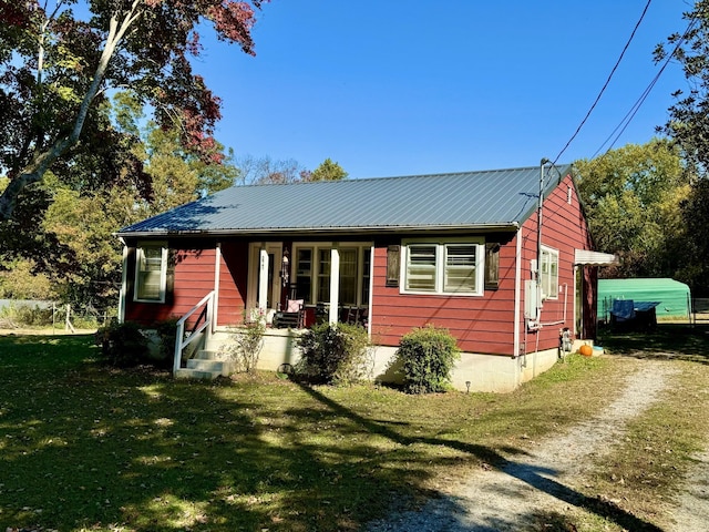 view of front of property with metal roof, a front lawn, a porch, and driveway