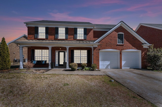 traditional-style house featuring concrete driveway, a yard, brick siding, and covered porch