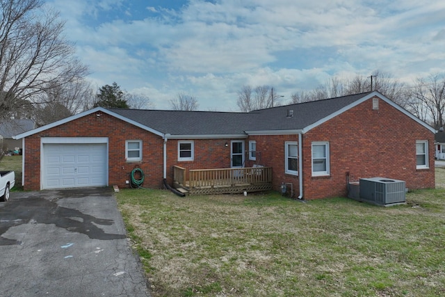 rear view of property with brick siding, aphalt driveway, central air condition unit, a lawn, and a garage