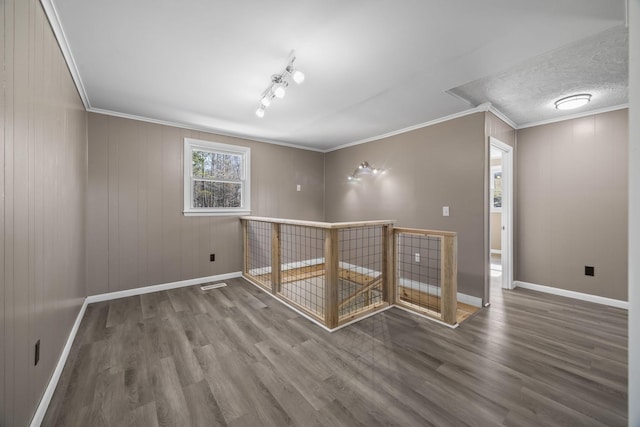 unfurnished room with wood finished floors, baseboards, and ornamental molding