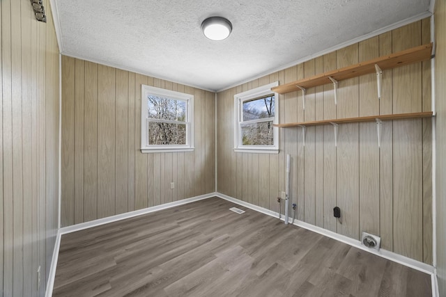 empty room with visible vents, wood finished floors, baseboards, and a textured ceiling