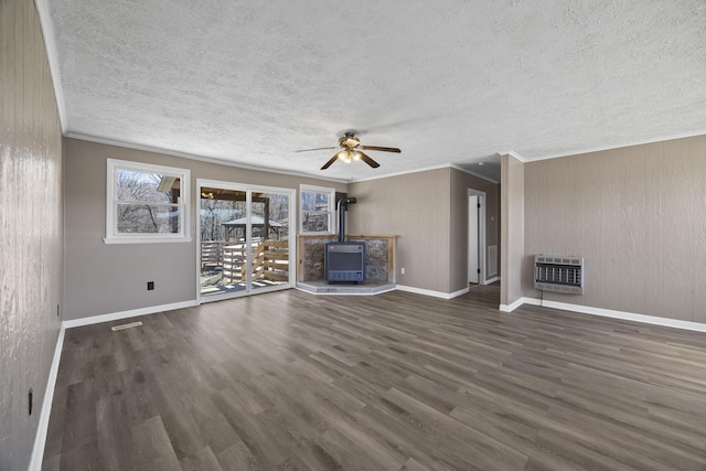 unfurnished living room with ornamental molding, a textured ceiling, a wood stove, and wood finished floors