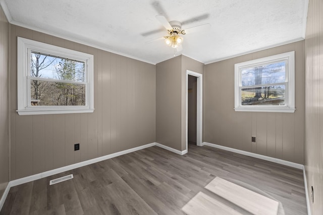 unfurnished bedroom featuring a textured ceiling, wood finished floors, visible vents, and baseboards