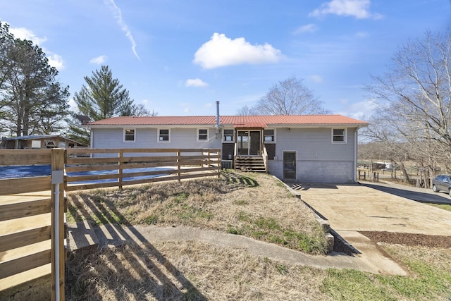 ranch-style house featuring metal roof and fence