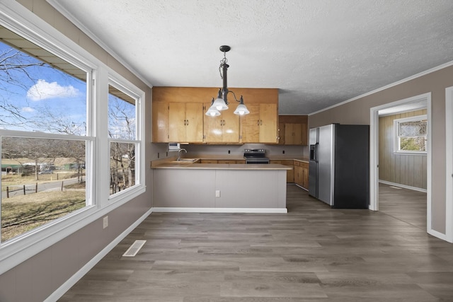 kitchen with visible vents, a peninsula, a sink, ornamental molding, and stainless steel appliances