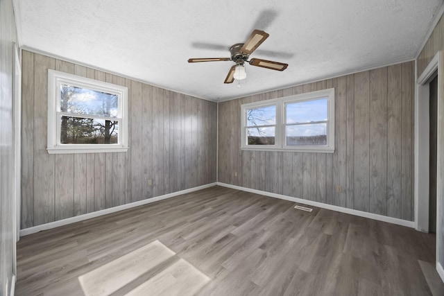 spare room with visible vents, a textured ceiling, baseboards, and wood finished floors