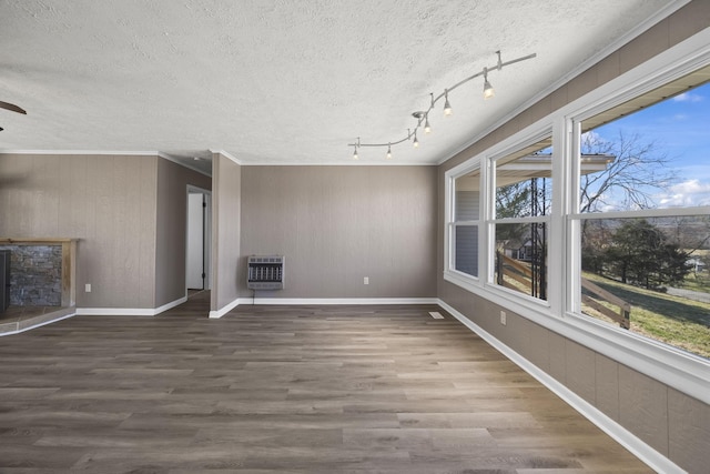 unfurnished living room with a textured ceiling, heating unit, wood finished floors, and ornamental molding