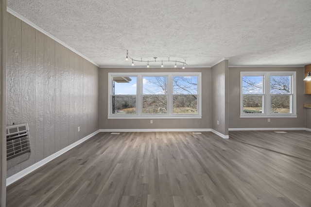 interior space with crown molding, baseboards, wood finished floors, heating unit, and a textured ceiling