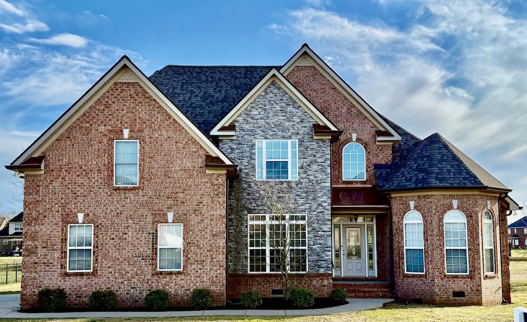 view of front facade featuring brick siding, roof with shingles, and crawl space