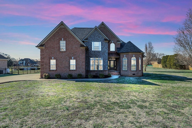 traditional home featuring brick siding, a shingled roof, fence, a yard, and crawl space