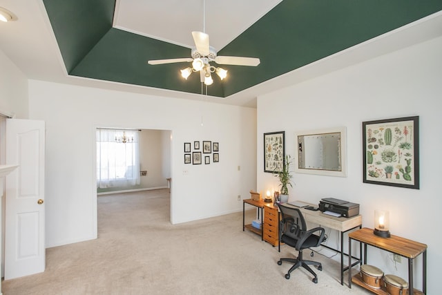 carpeted office with ceiling fan, baseboards, lofted ceiling, and a tray ceiling