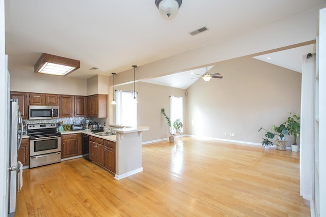 kitchen with visible vents, a peninsula, light countertops, light wood-style floors, and appliances with stainless steel finishes