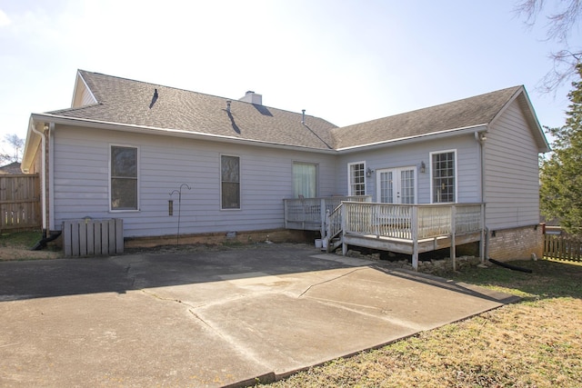 rear view of house with a deck, fence, french doors, and a chimney