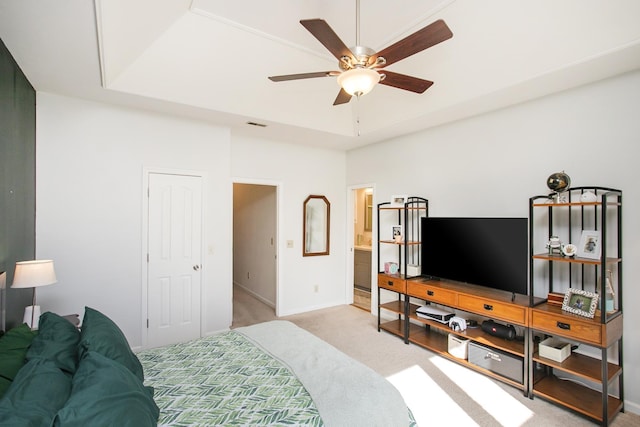 bedroom featuring visible vents, baseboards, light colored carpet, a tray ceiling, and a ceiling fan