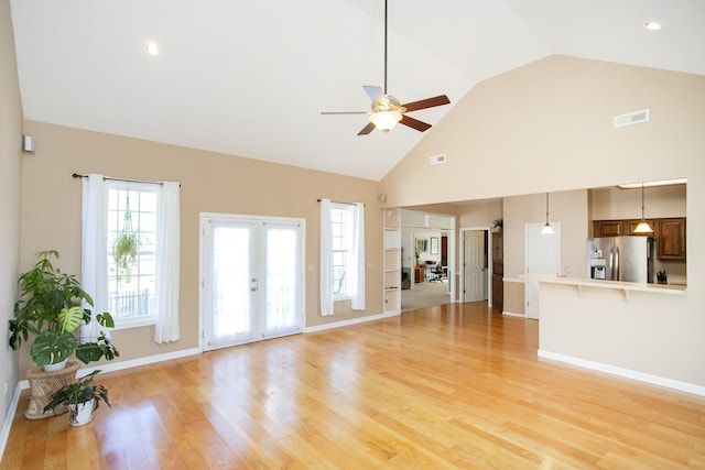 unfurnished living room with ceiling fan, french doors, high vaulted ceiling, and light wood-style floors