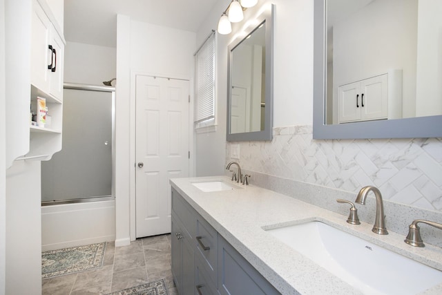 bathroom with double vanity, combined bath / shower with glass door, backsplash, and a sink