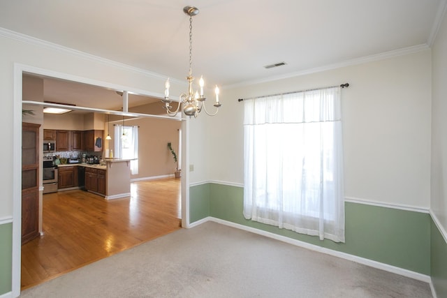 unfurnished dining area with visible vents, light wood-style flooring, crown molding, baseboards, and a chandelier